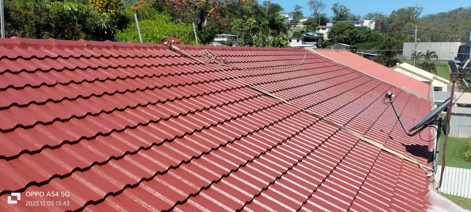 A Worker on A Ladder Paints a Roof — Priority Painters in Tannum Sands, QLD