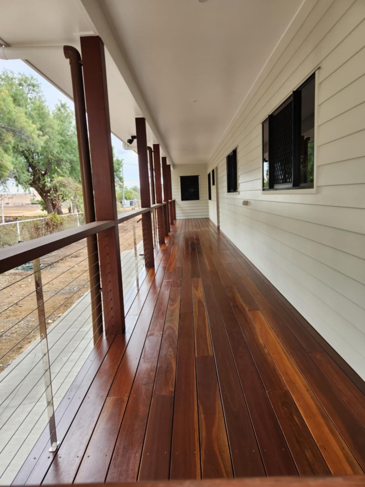 A Long, Covered Wooden Veranda With a Wire Railing — Priority Painters in Gladstone Central, QLD