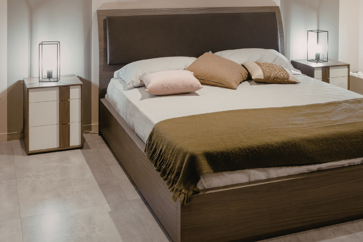 Weißes Schlafzimmer mit Bett, Pflanzen und geflochtenen Lampen.