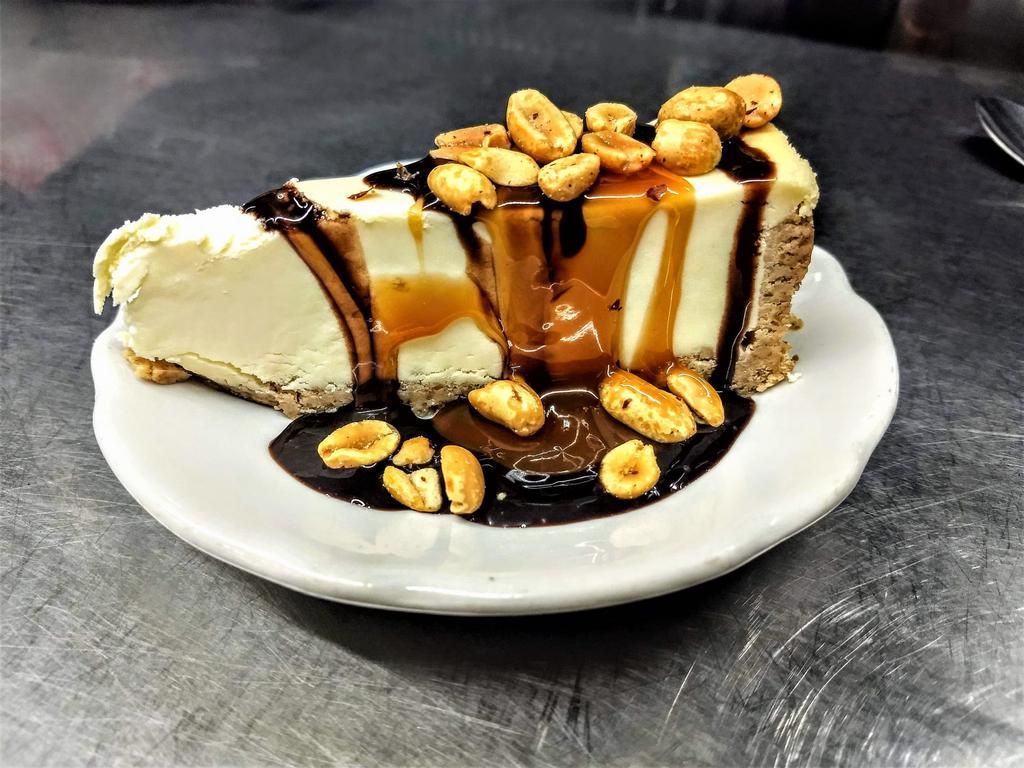 a slice of cheesecake with caramel and peanuts on top