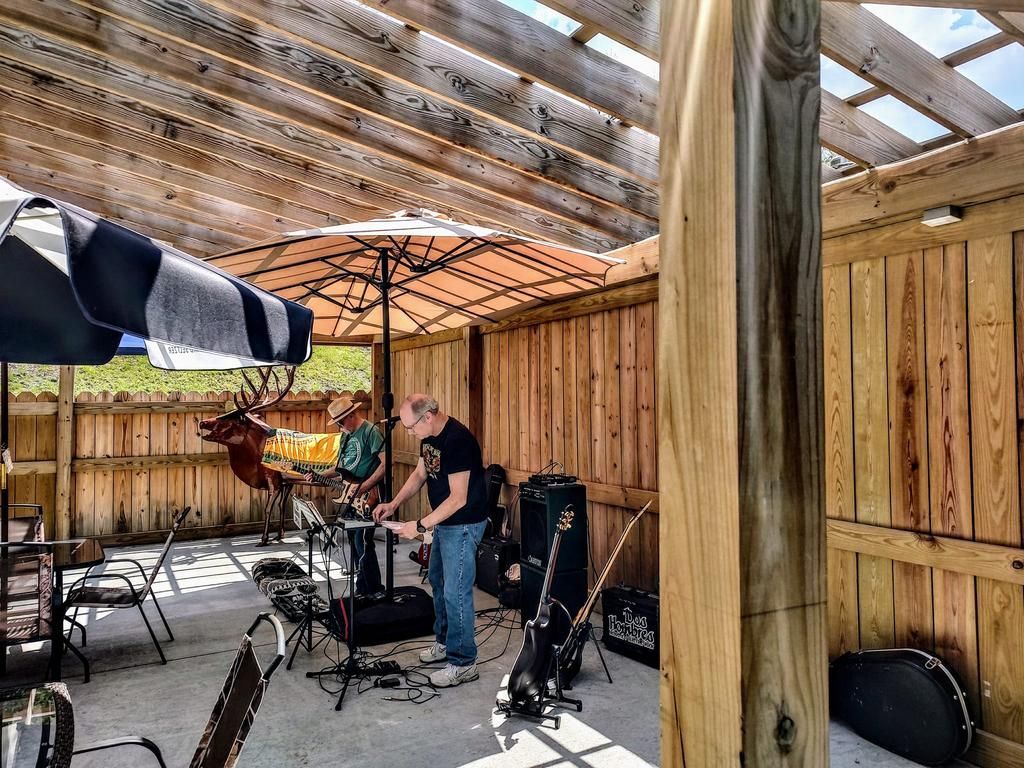a man playing a guitar under an umbrella in front of a sign that says fender
