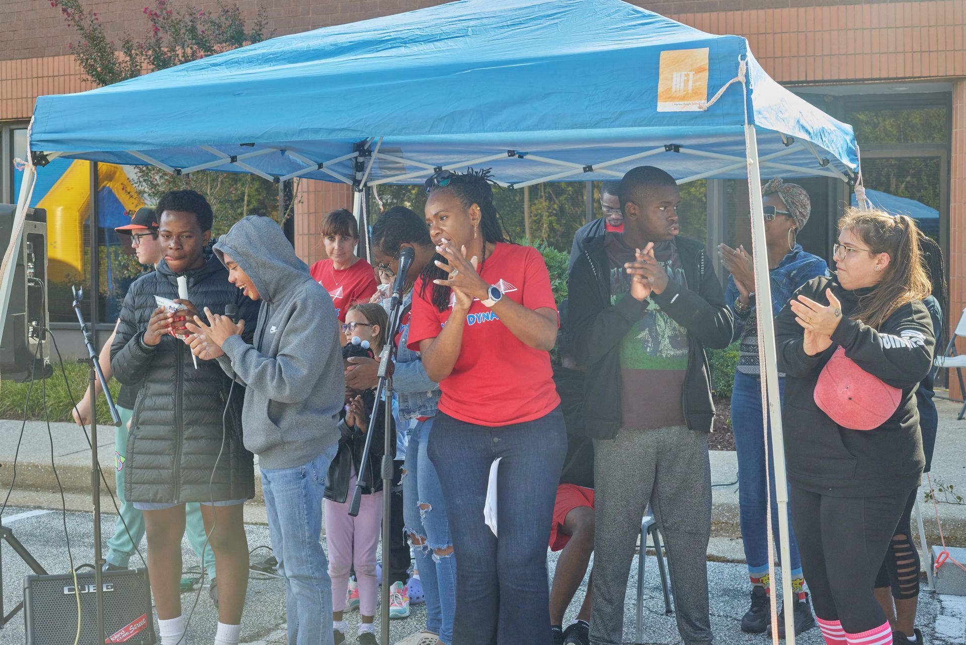 Two people in red shirts pose for a photo outside a building.
