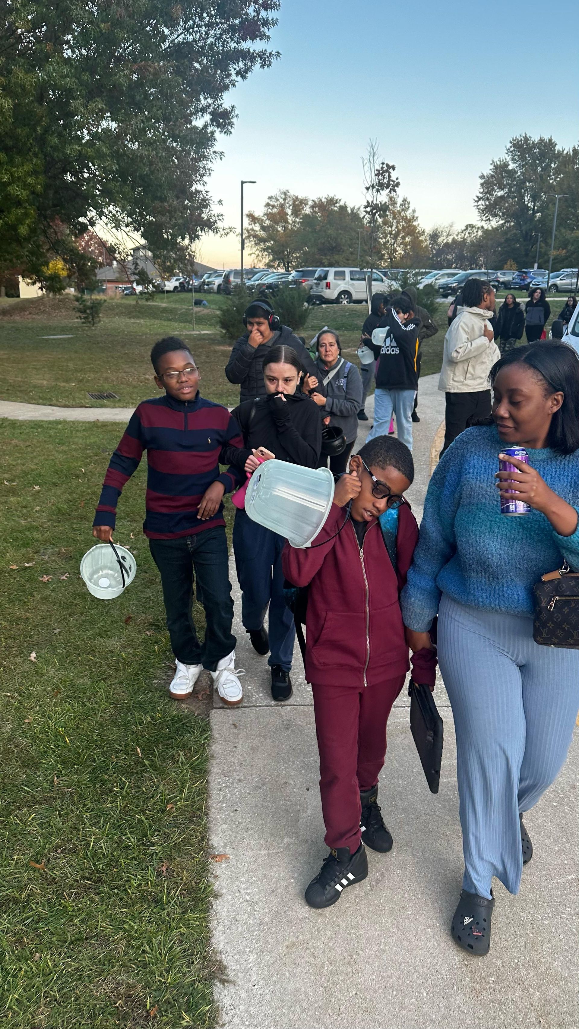 People walking on a sidewalk, possibly leaving a school. 