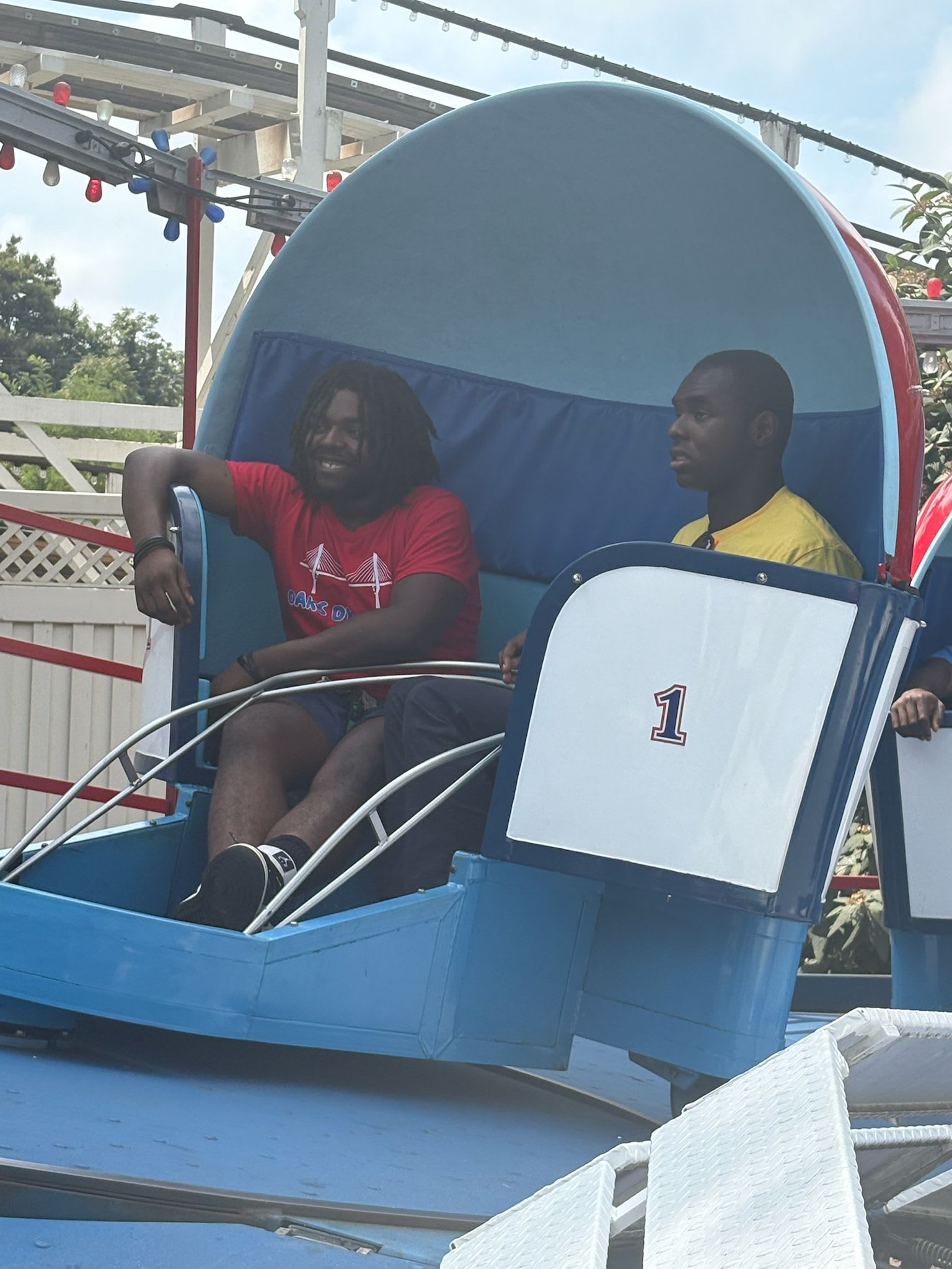 Two people ride a blue and white amusement park ride. 