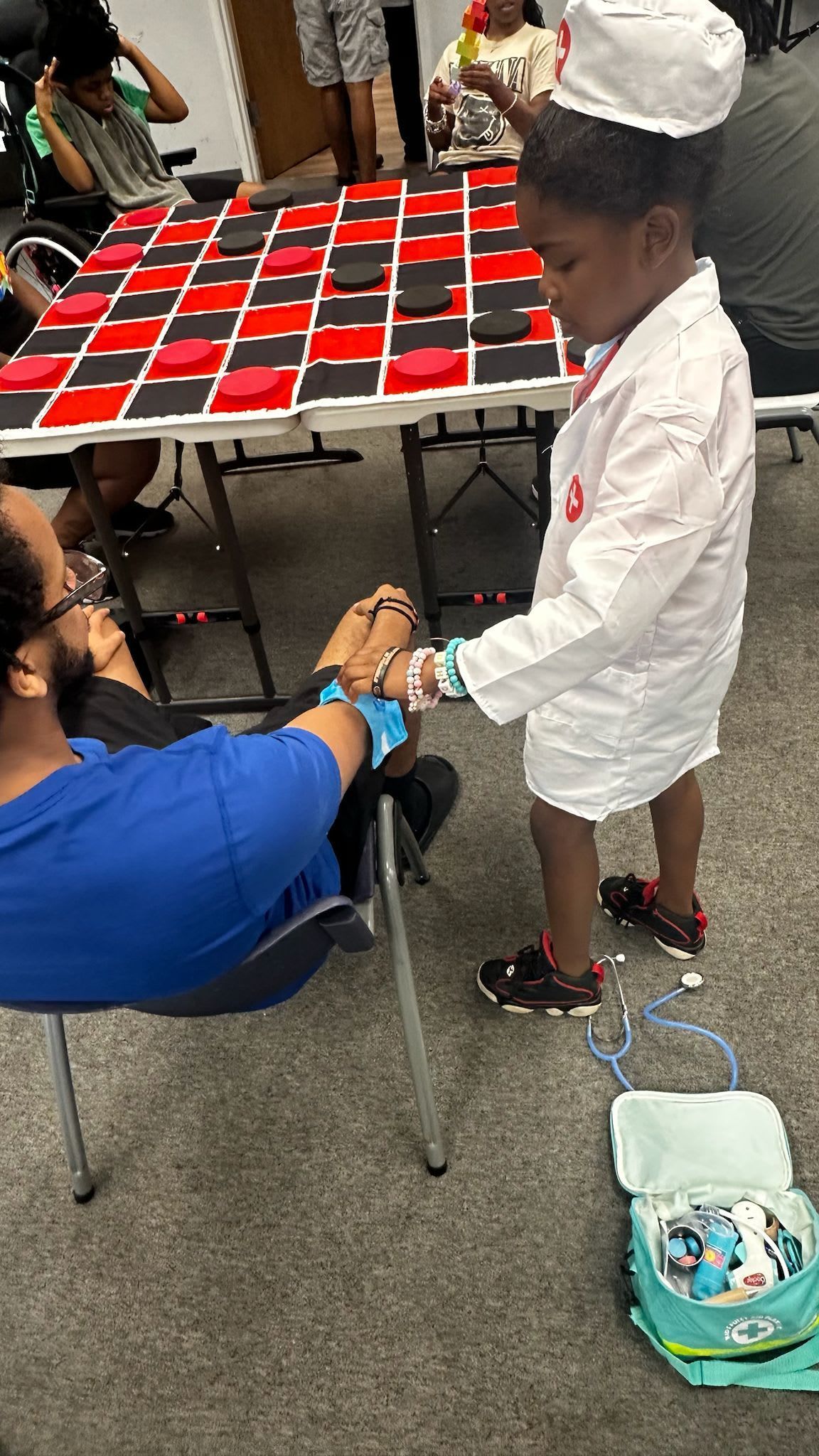 Child in doctor costume examining an adult's wrist.