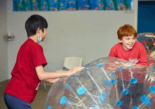 Two boys in red shirts play with bubble balls indoors. 