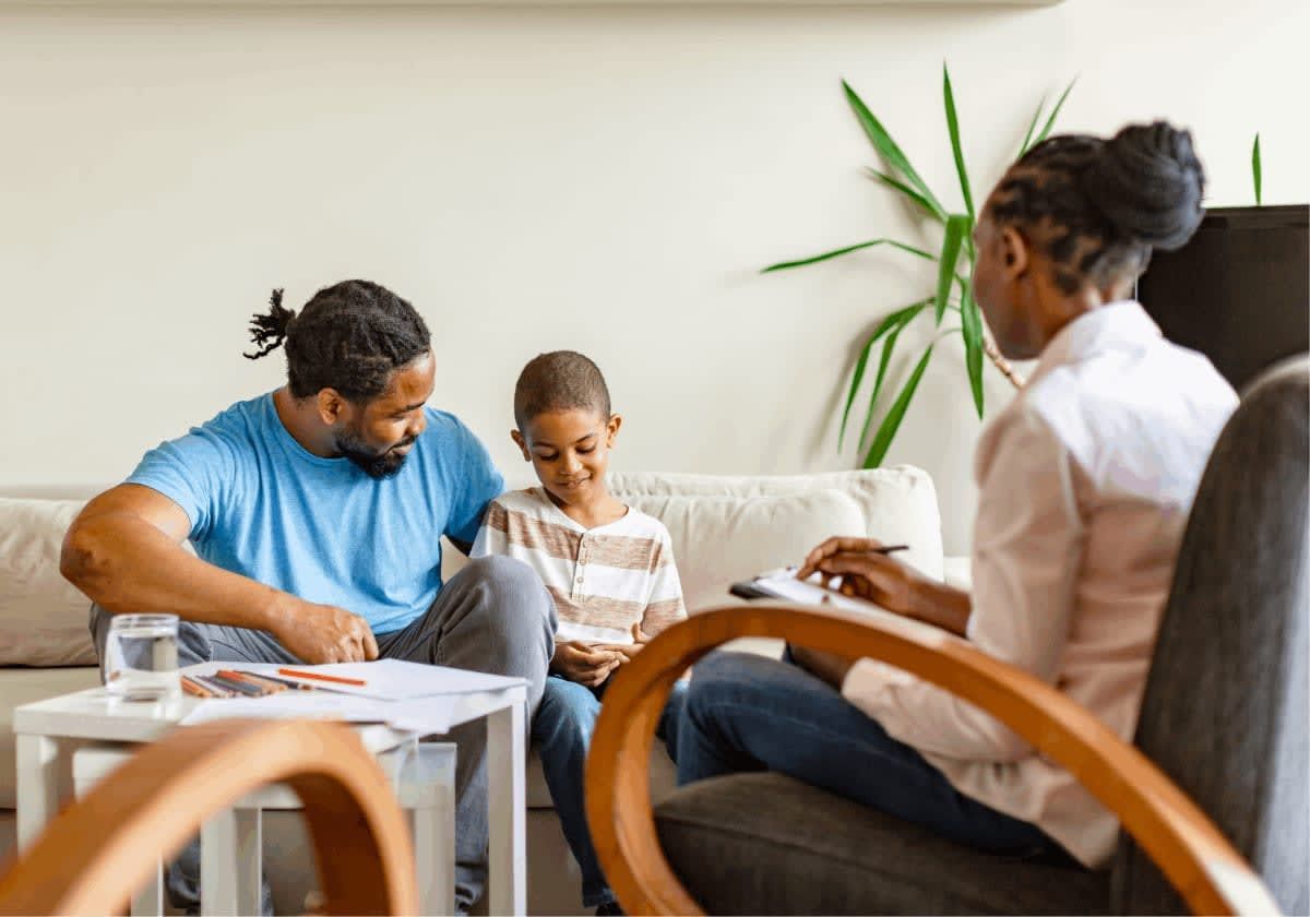Father and child on a couch with a therapist. 