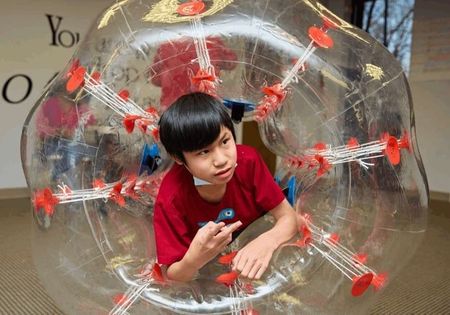 Boy in a transparent bubble suit, indoors.