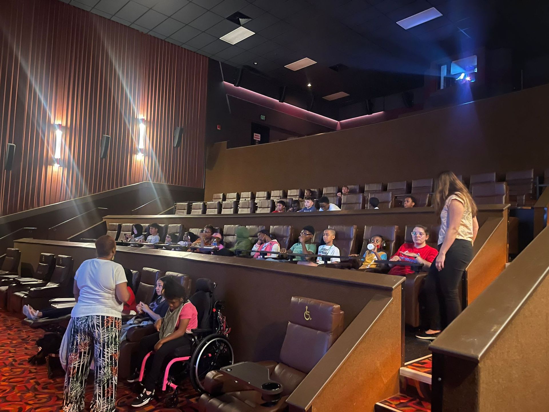 Children and adults in a tiered movie theater. 
