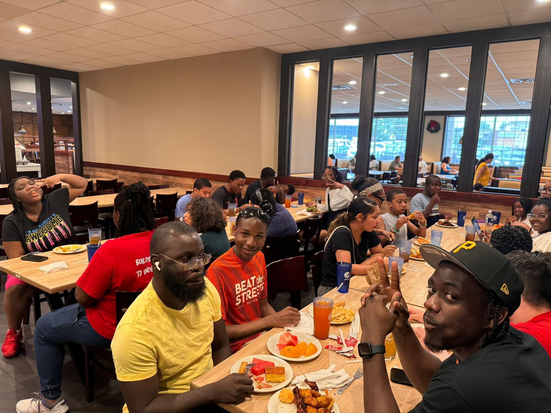 People eating and conversing at tables in a brightly lit cafeteria. 