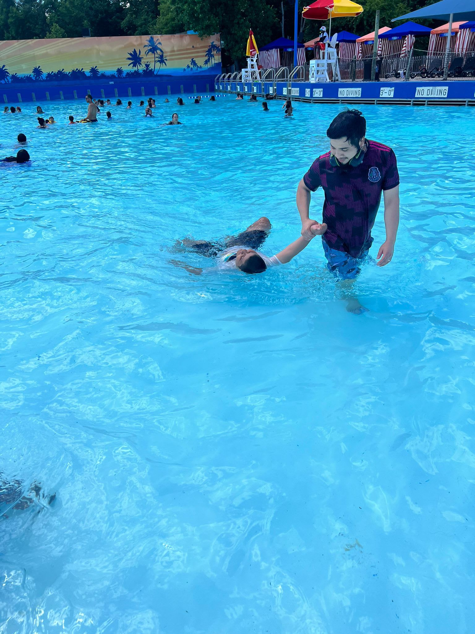 Man helping another person in a wave pool. 