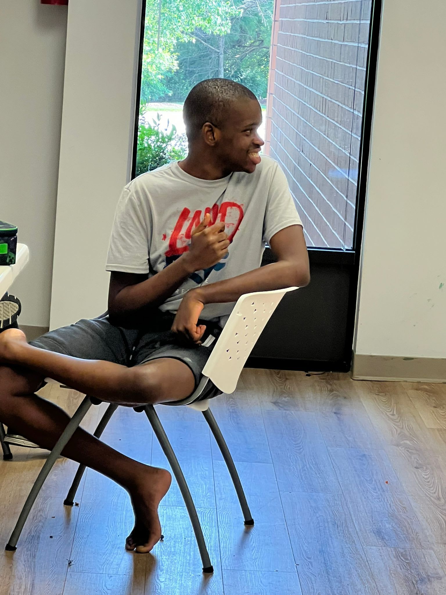 Person sitting in a chair, looking right and smiling.