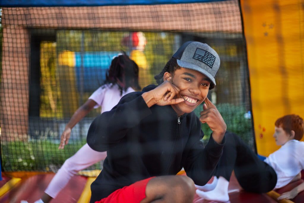Boy in cap makes a playful face, inside a bouncy castle.