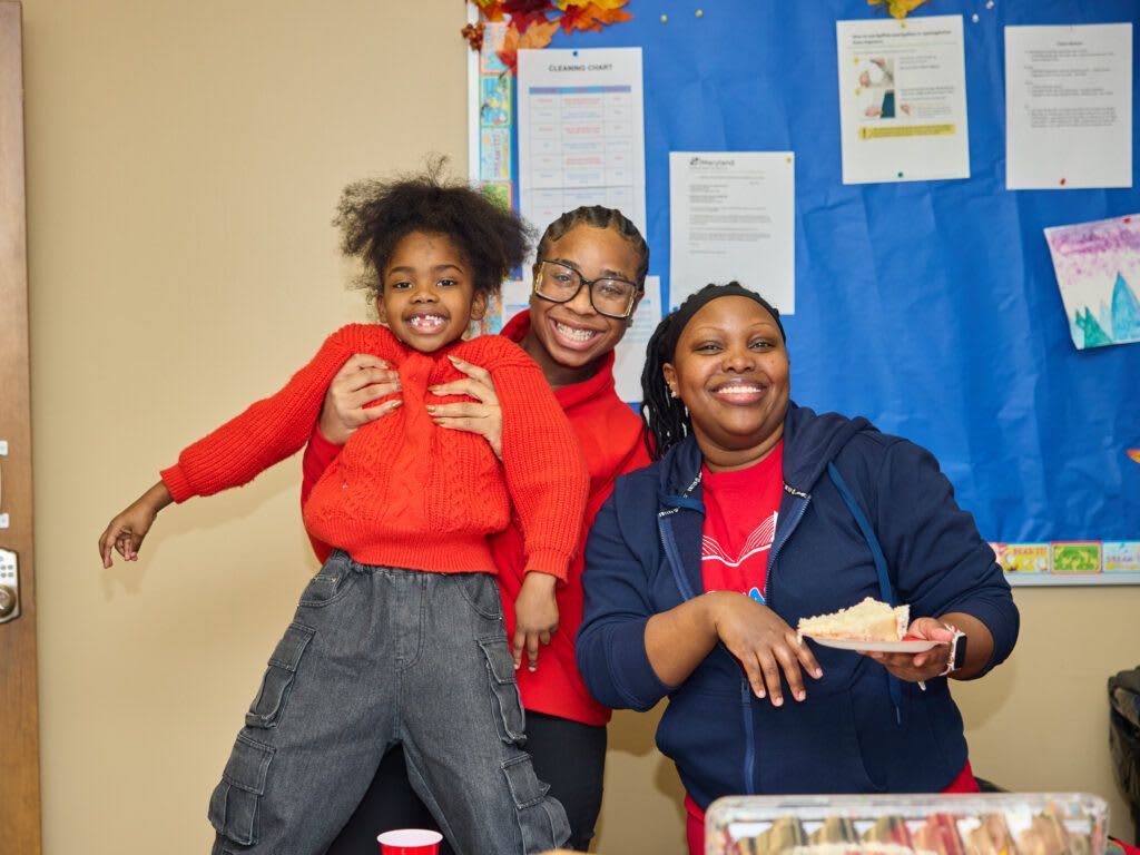 Three smiling people pose together. 