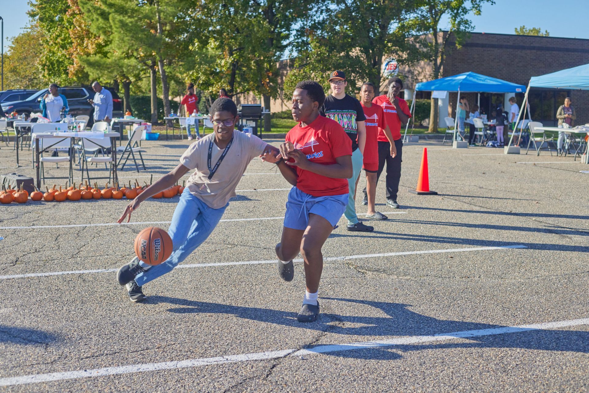 Two people playing basketball outdoors. 