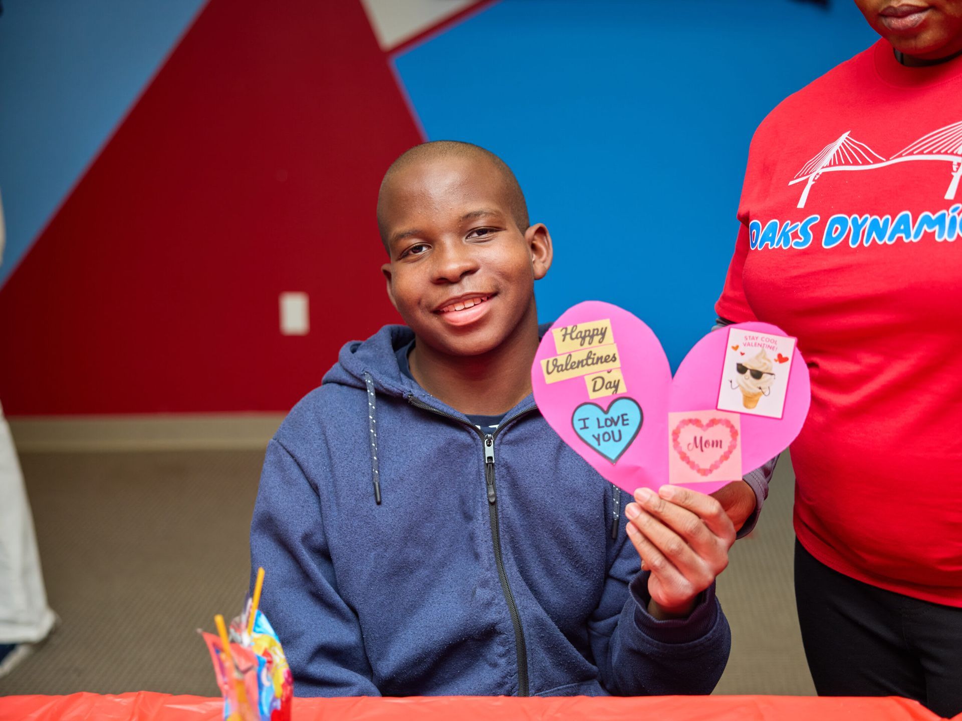 Young person holds a Valentine's Day heart-shaped card, smiling.