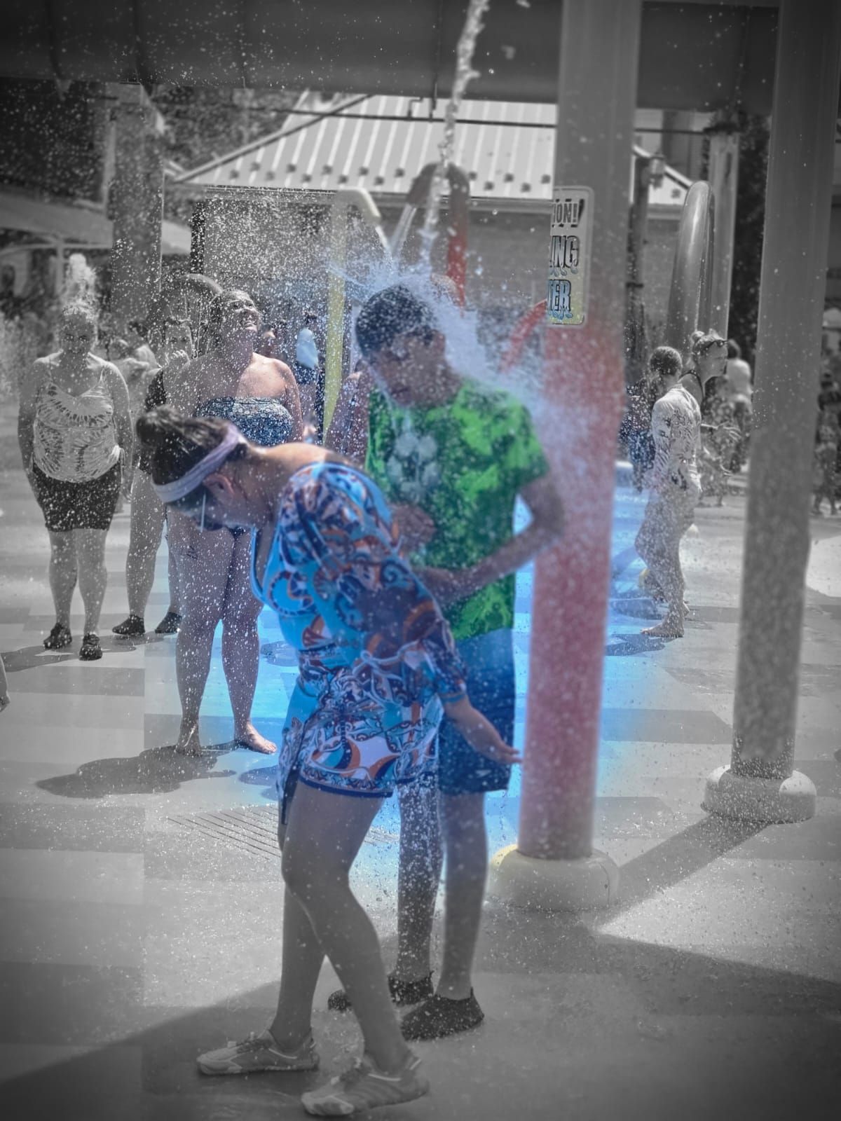 People under a water shower at a water park. 
