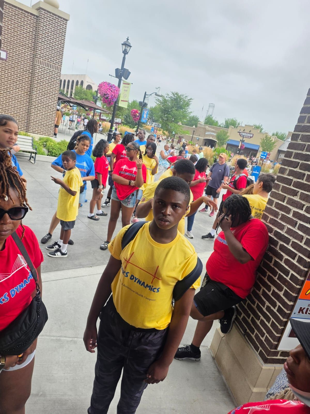 Group of people in colorful shirts outside a building; some look at camera. 