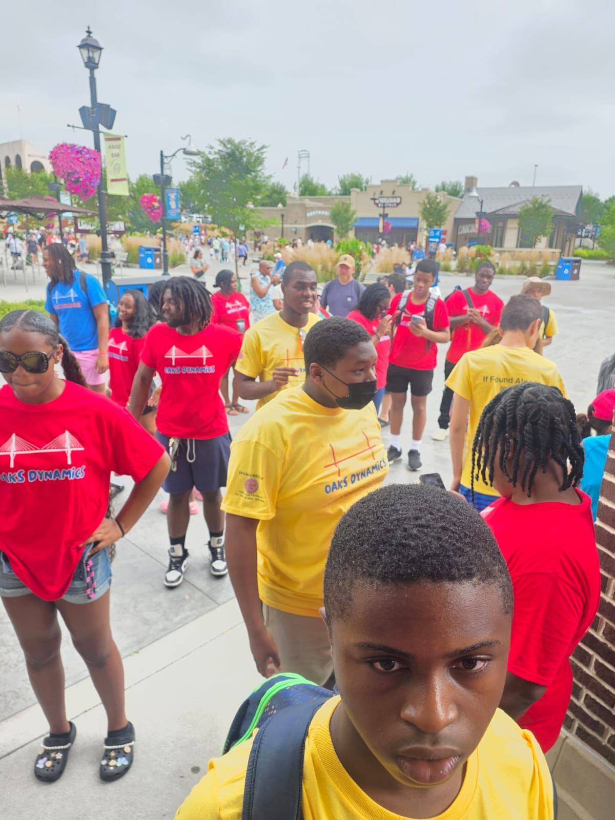 Group of people in red and yellow shirts outside, some wearing masks.