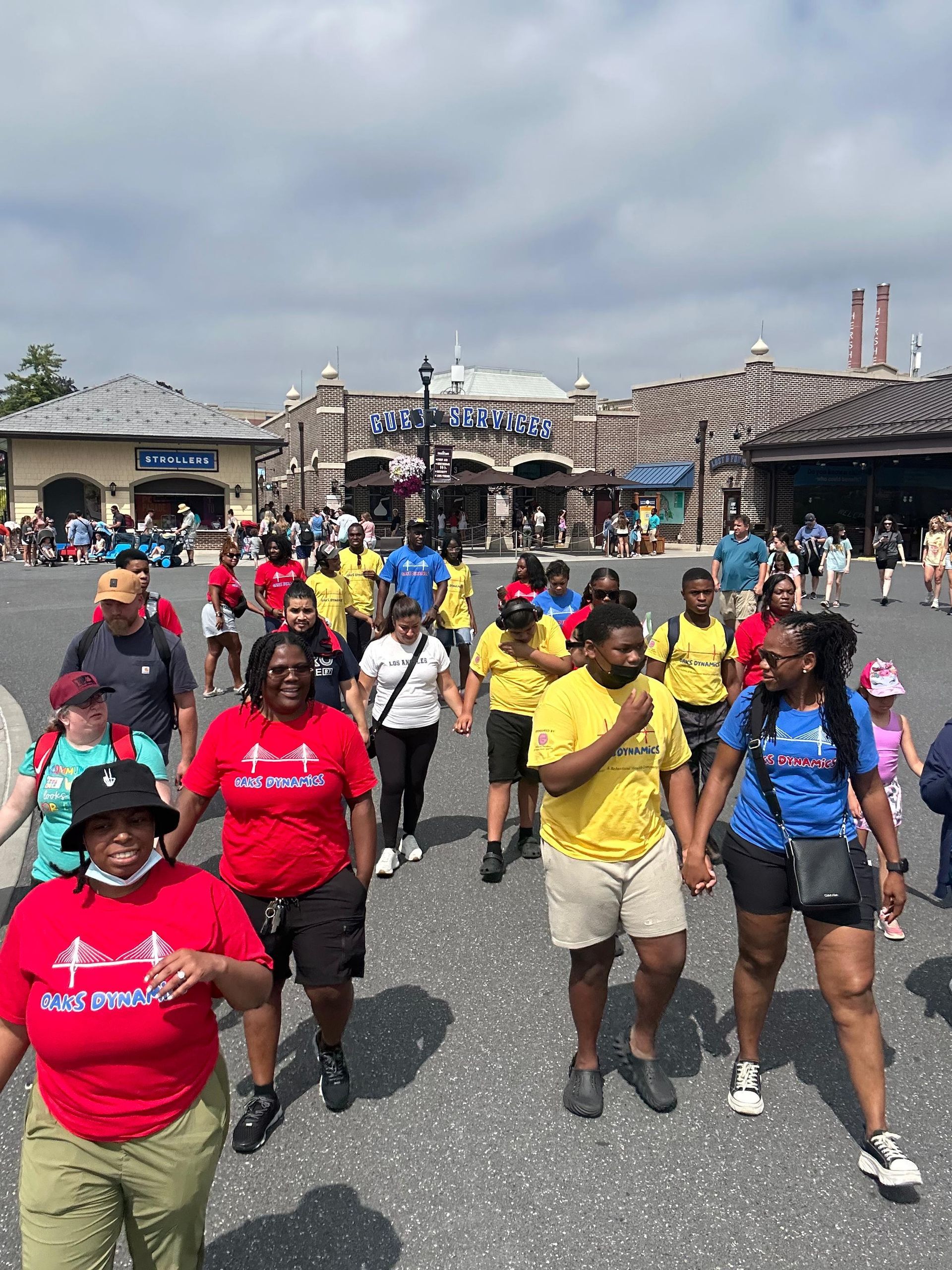People walking together outdoors, some wearing red and yellow shirts. 