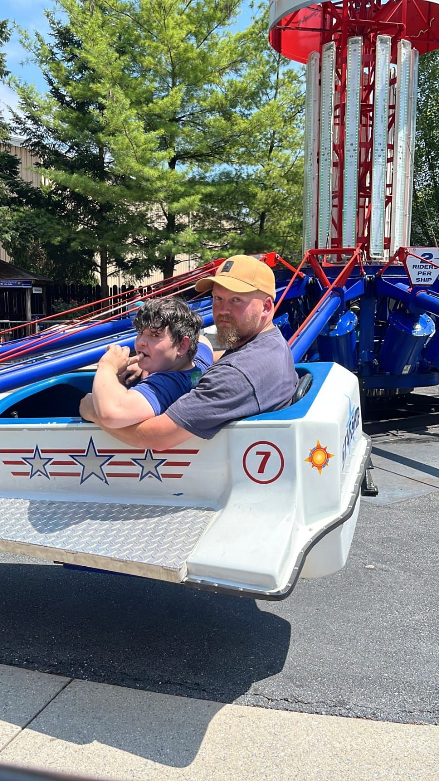 Two people in a carnival ride car. The car is white with red and blue accents. 