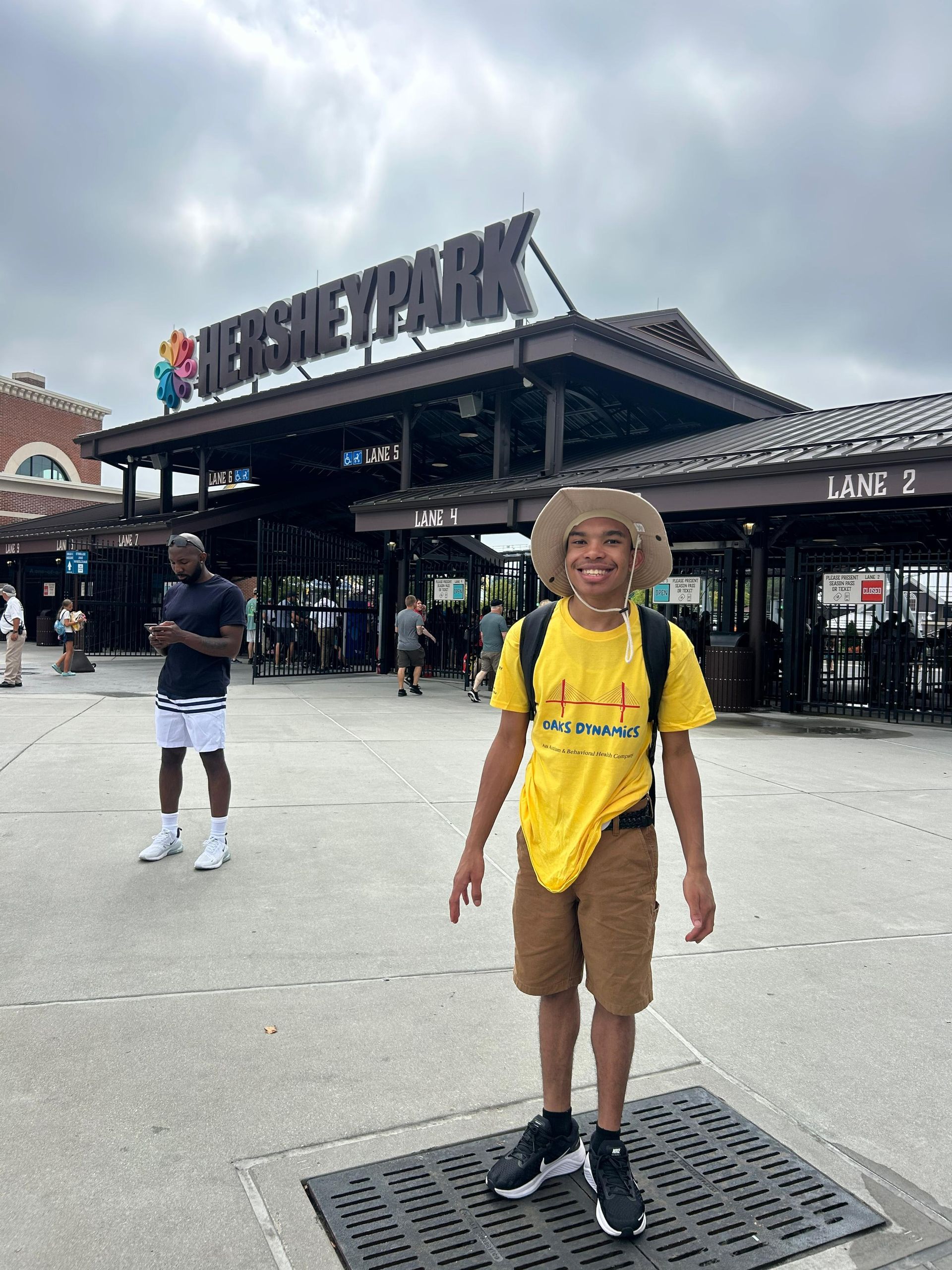 A person in yellow shirt and hat stands in front of Hersheypark entrance. 