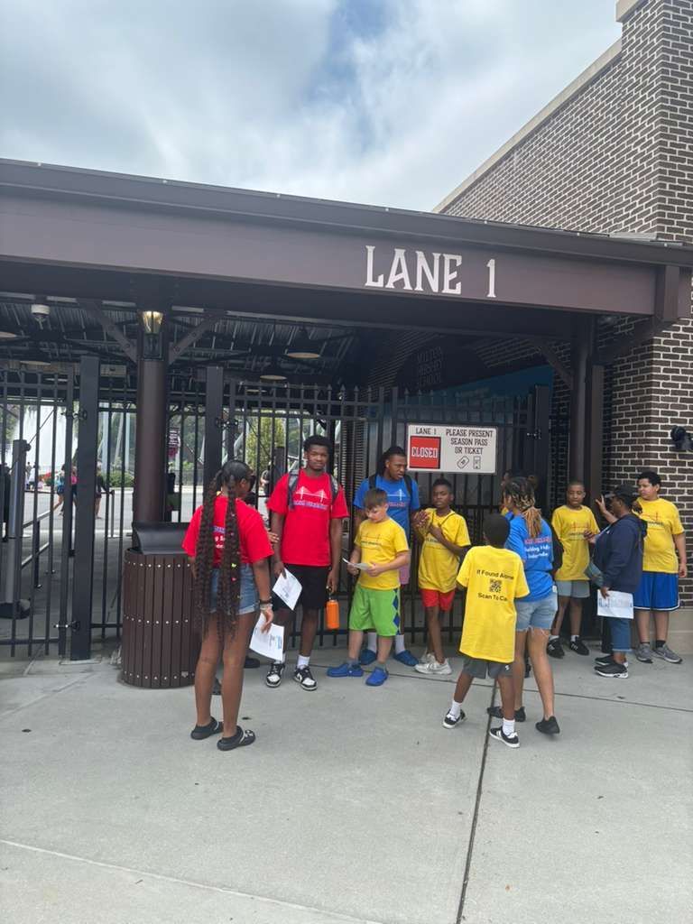 Group of children, some in yellow shirts, gather outside 
