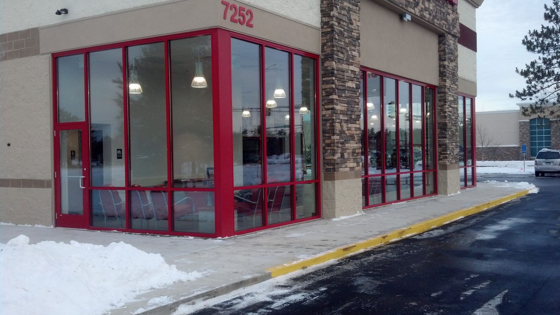 Exterior of commercial building with red framed windows and snow.