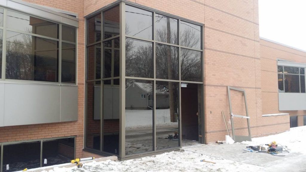 Exterior building with a glass-walled entrance, brick facade, and snow.