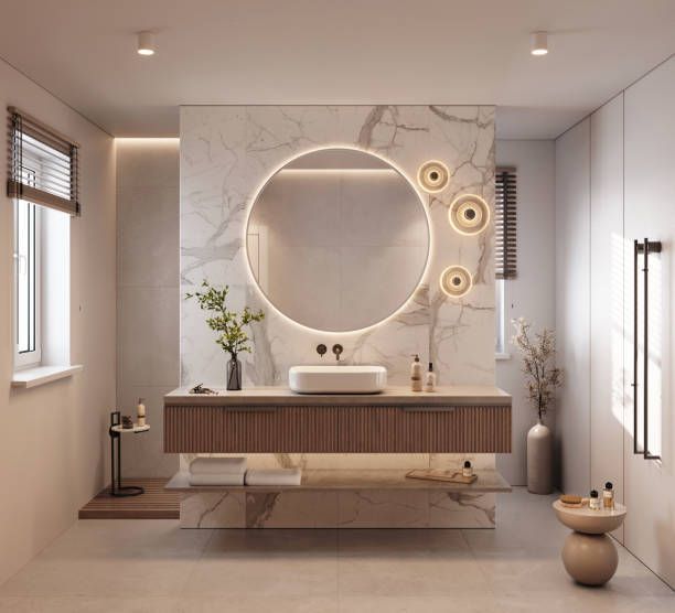 Modern bathroom with marble accents, floating vanity, circular mirror with lights.