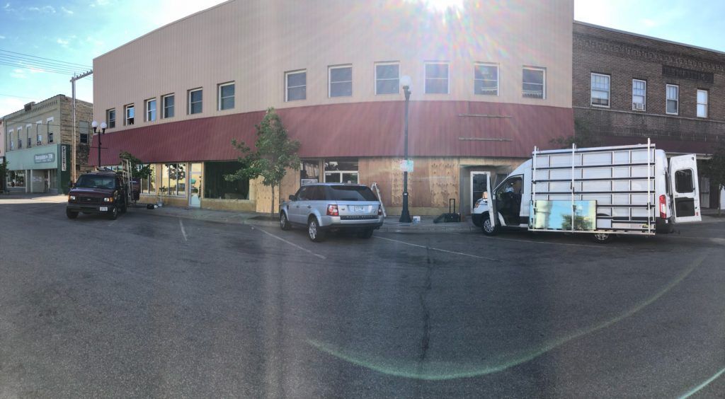 Street scene with a building with a red awning and vehicles parked on the street.