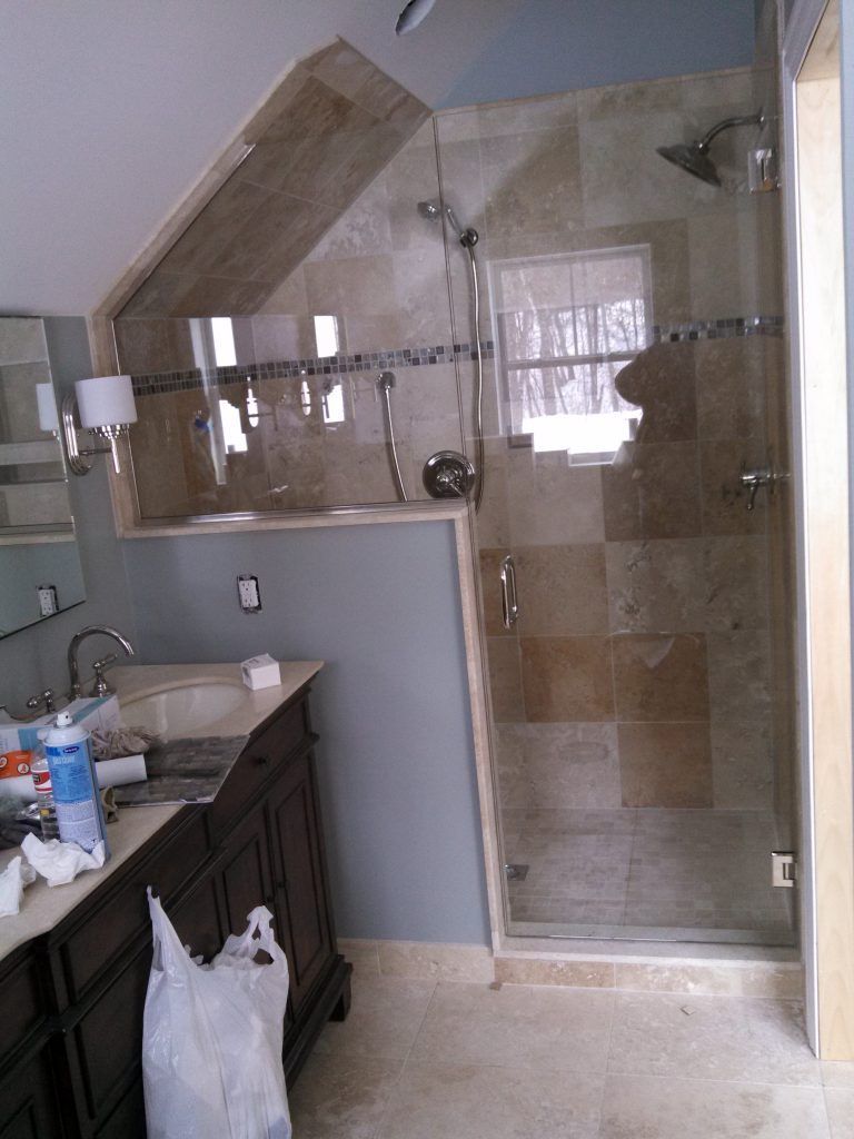 Bathroom renovation: shower with glass door, vanity with sink, and tiled walls.