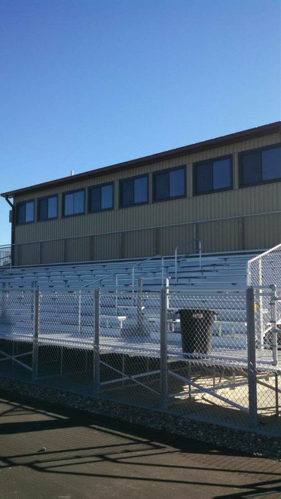 Bleachers and a building with windows under a clear, blue sky.