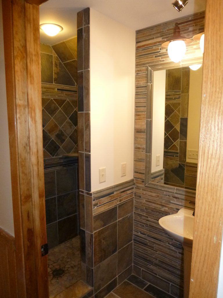 Bathroom with tiled shower, vanity, and mirror visible through a doorway; neutral tones.