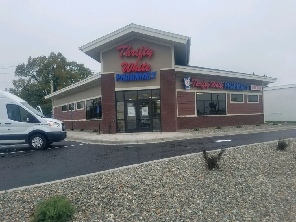 Exterior of Thrifty White Pharmacy with a white van parked nearby.