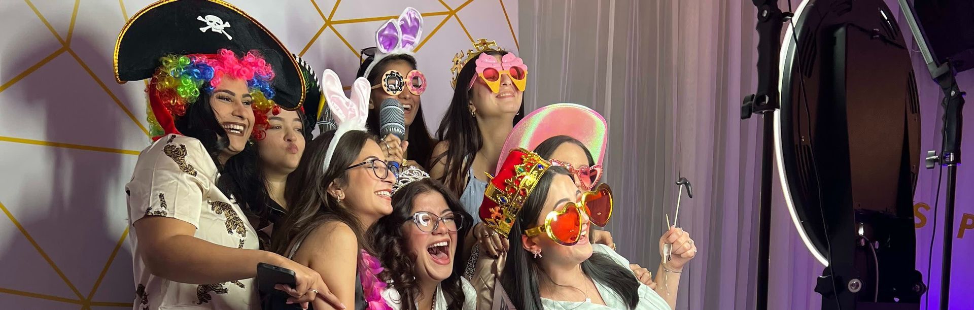 Group of smiling people with photo booth props pose for a photo.