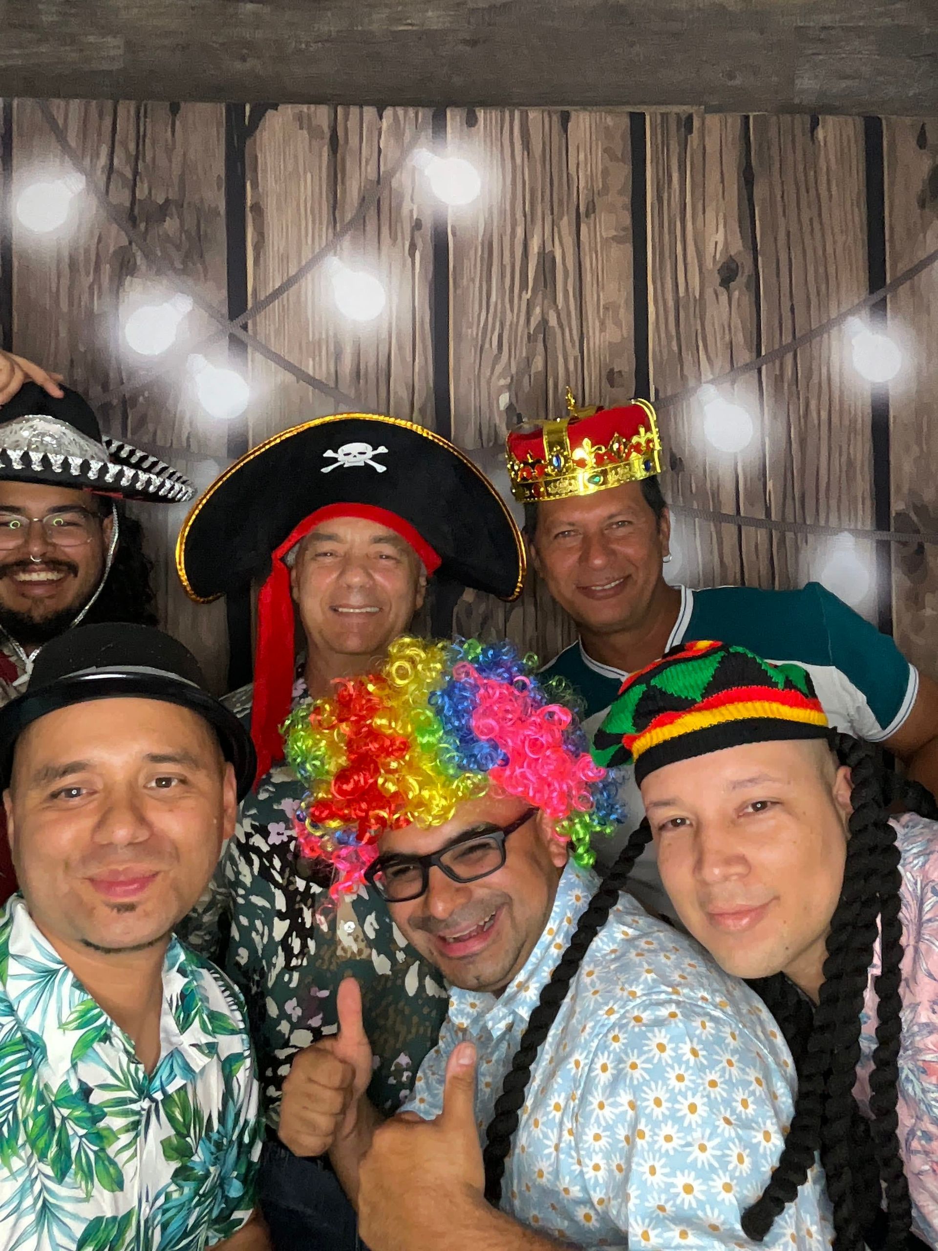 Couple embracing in front of a bokeh background. Man in hat and suspenders, woman in white dress, both smiling.