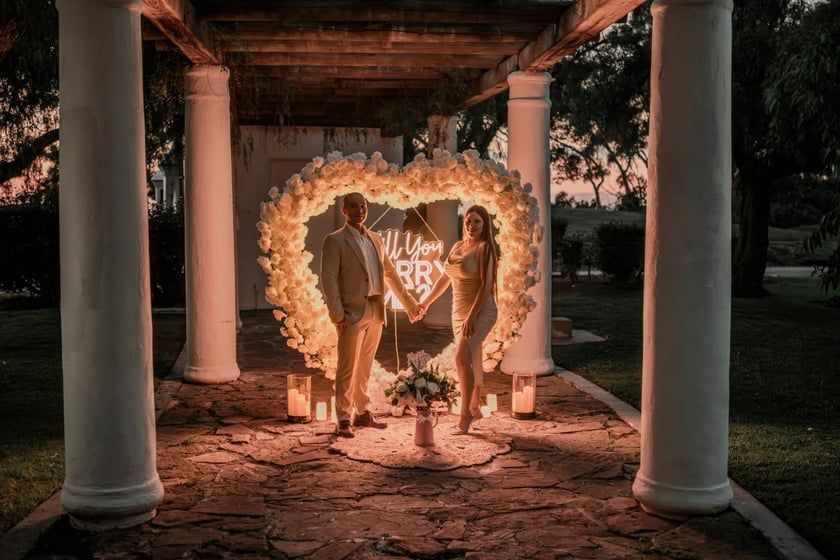 A group of people are posing for a picture in a photo booth with red roses in the background.