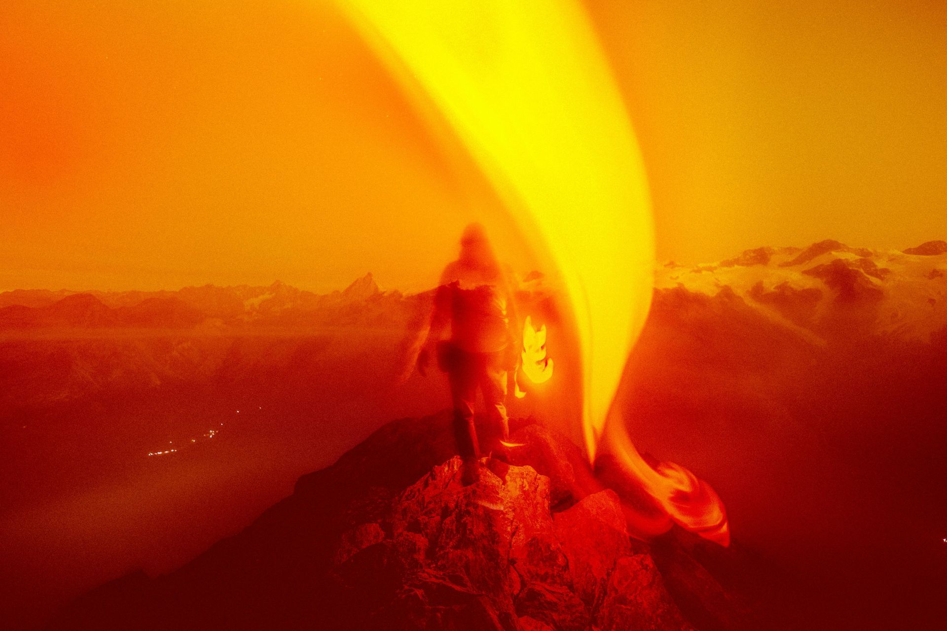 A person is standing on top of a volcano with a torch in their hand.