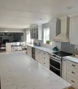 White kitchen with large island, stainless steel appliances, and white cabinets.