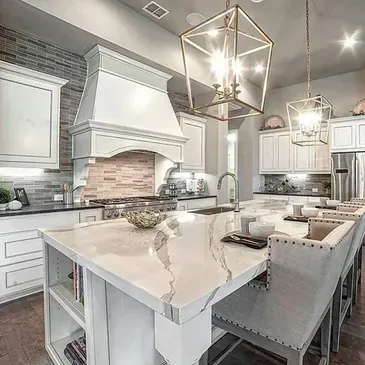 Modern kitchen with white cabinets, island, and pendant lighting.