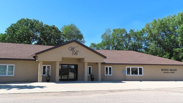 A tan building with a brown roof and a sign that says wing bales