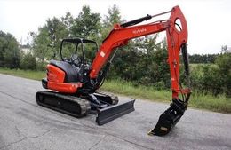 A small red excavator is parked on the side of a road.