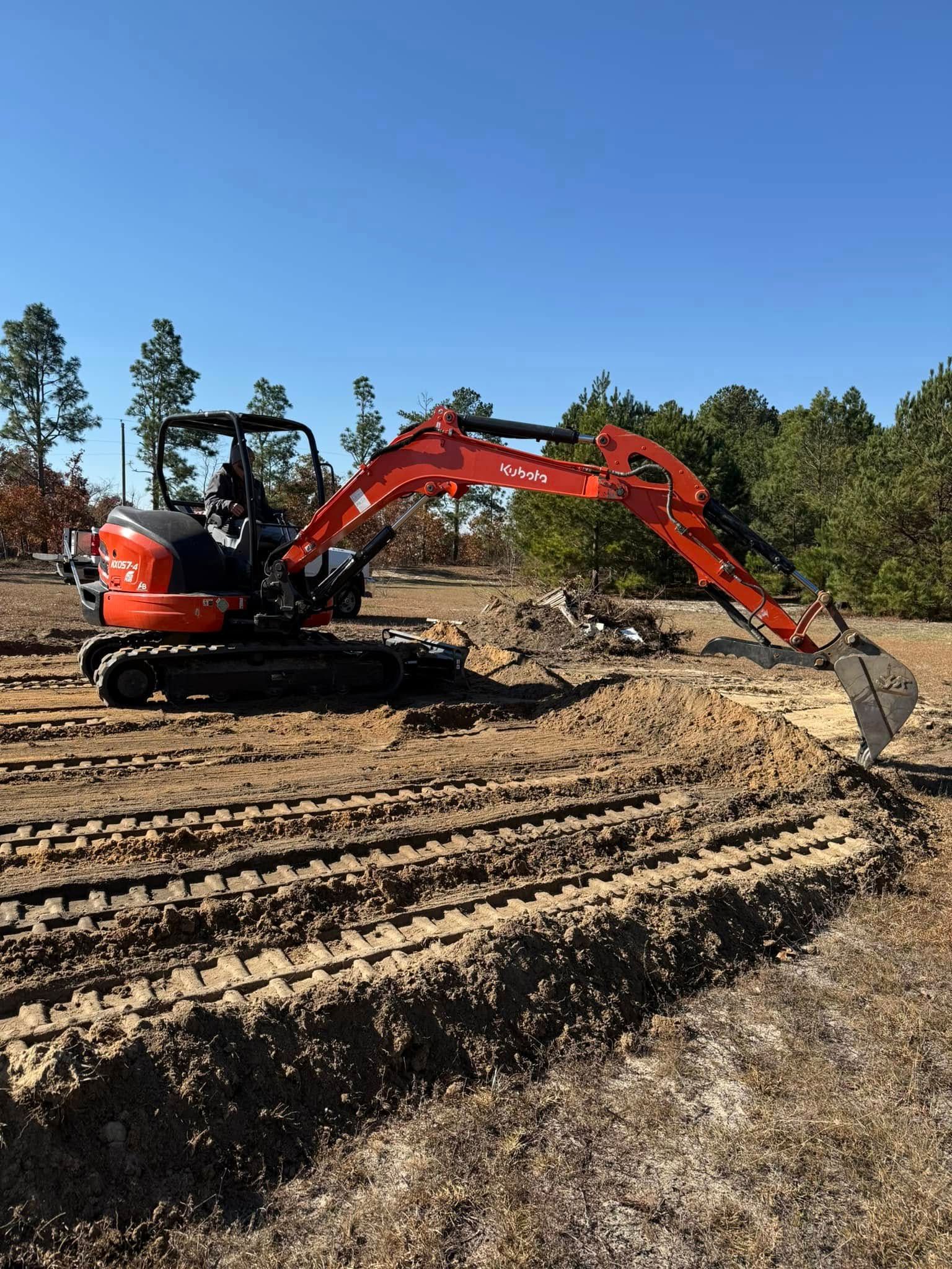 An orange excavator is digging a hole in a dirt field.