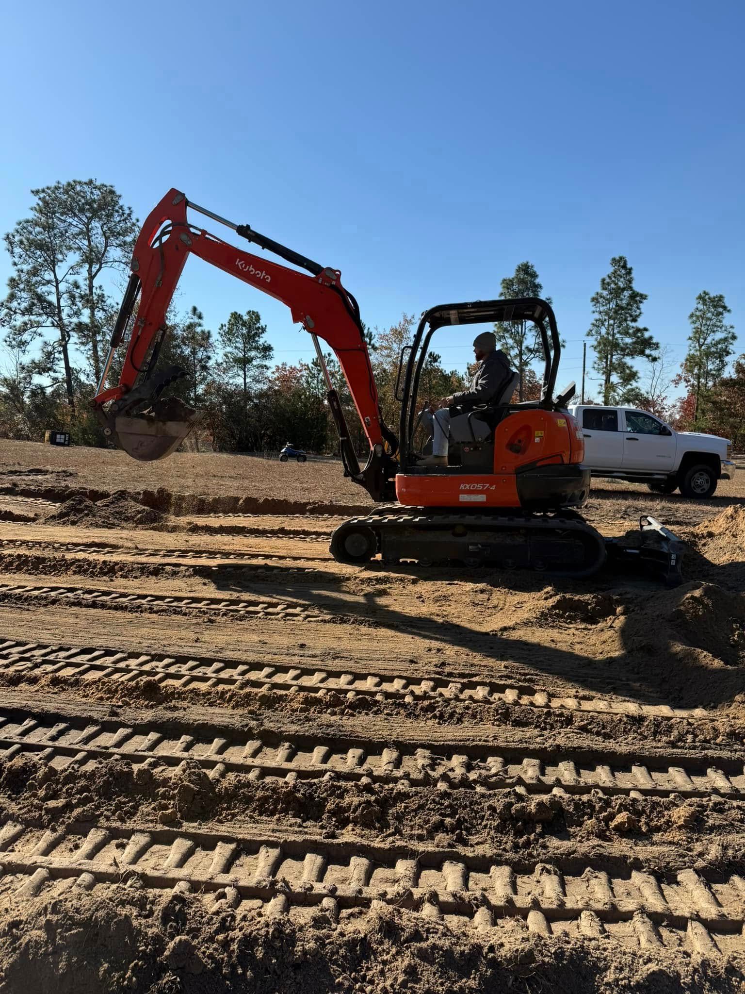An orange excavator is digging a hole in a dirt field.