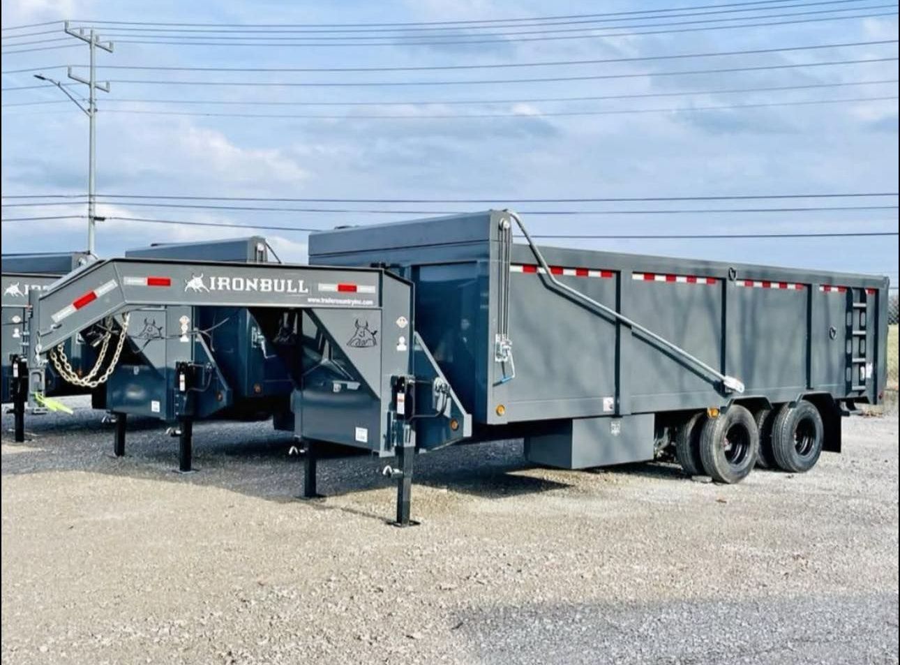 A dump trailer is parked in a gravel lot.