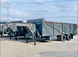 A dump trailer is parked in a gravel lot.