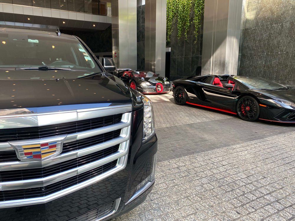 A cadillac and a lamborghini are parked in front of a building.