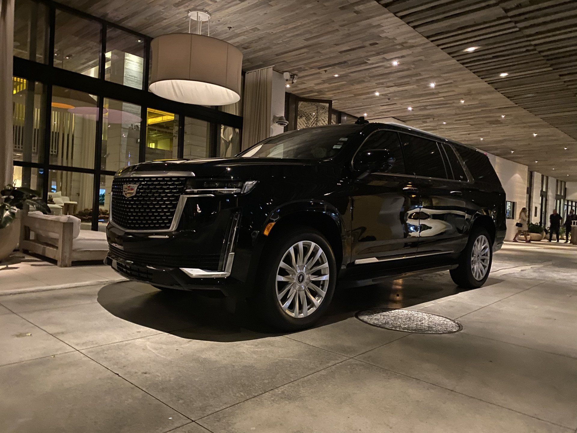 A black cadillac escalade is parked in a parking lot.