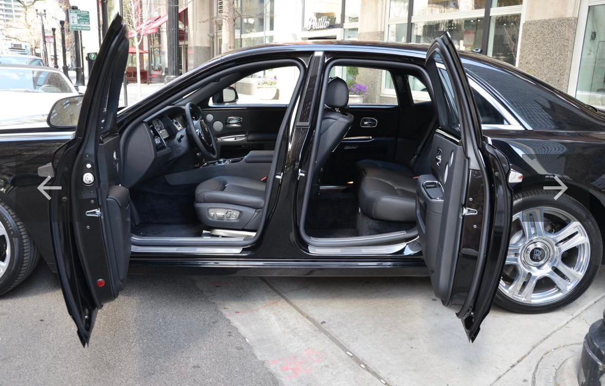 A black car with its doors open is parked on the sidewalk